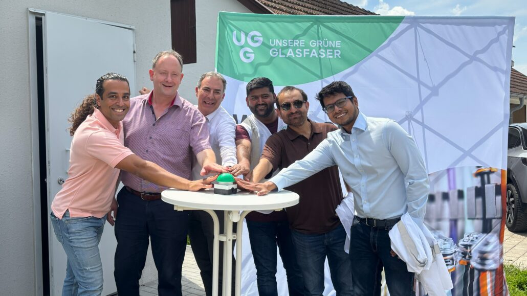Gruppenfoto von Mitarbeitern von Unsere Grüne Glasfaser bei einer feierlichen Veranstaltung zur Förderung von Glasfaser-Technologie.
